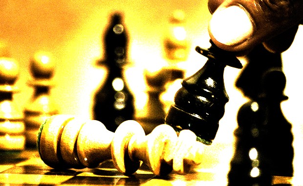 hotoffthechess-classic-game Picture of chess board, king lying down, a hand moving another piece. Hot off the chess, classic game.